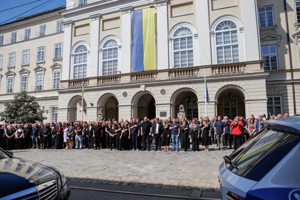 Люди зібрані під будівлею з прапором України