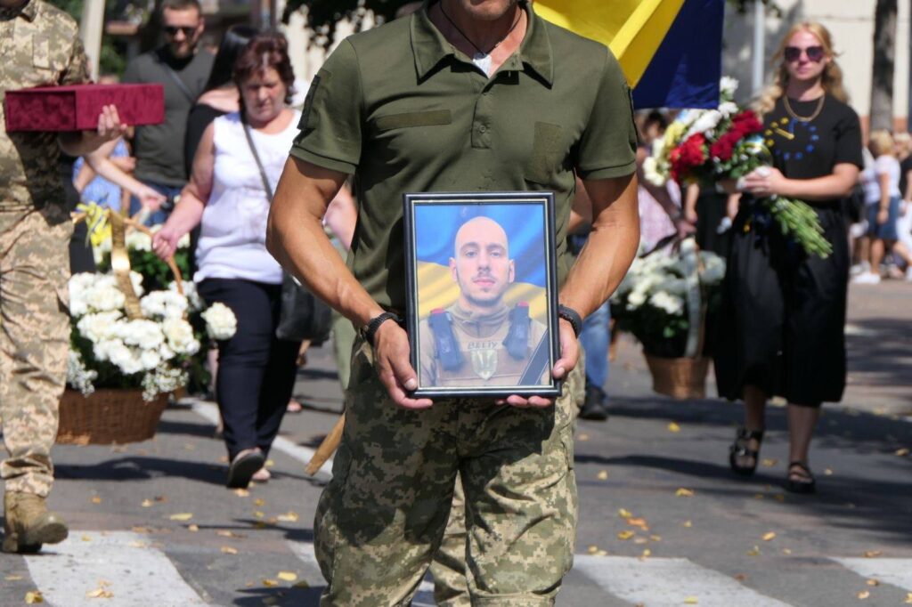 Військовий тримає портрет на церемонії прощання.