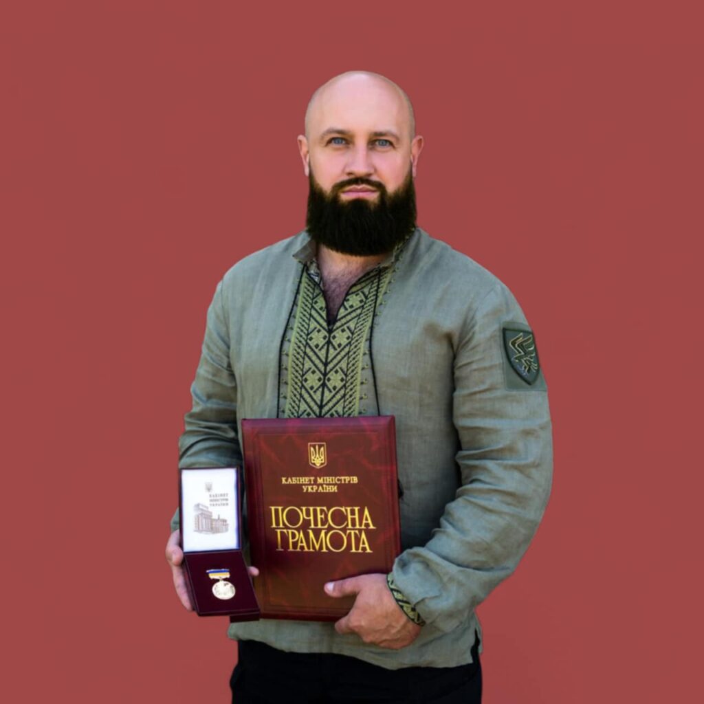 Чоловік вишиванка, грамота, медаль, червоне тло