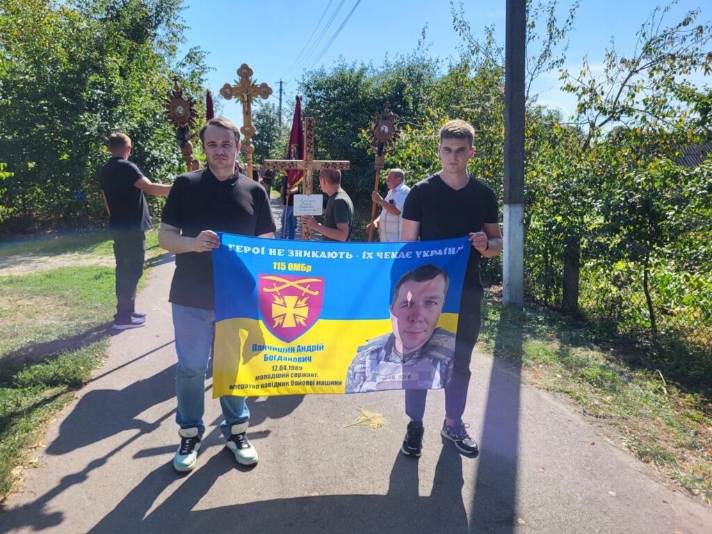 Люди тримають банер з героєм України.