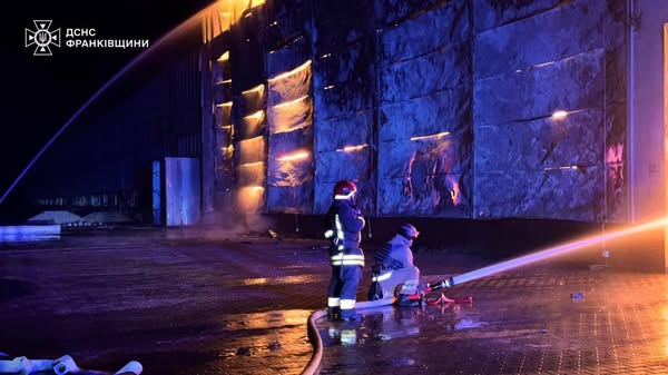 Пожежники гасять пожежу вночі біля будівлі.