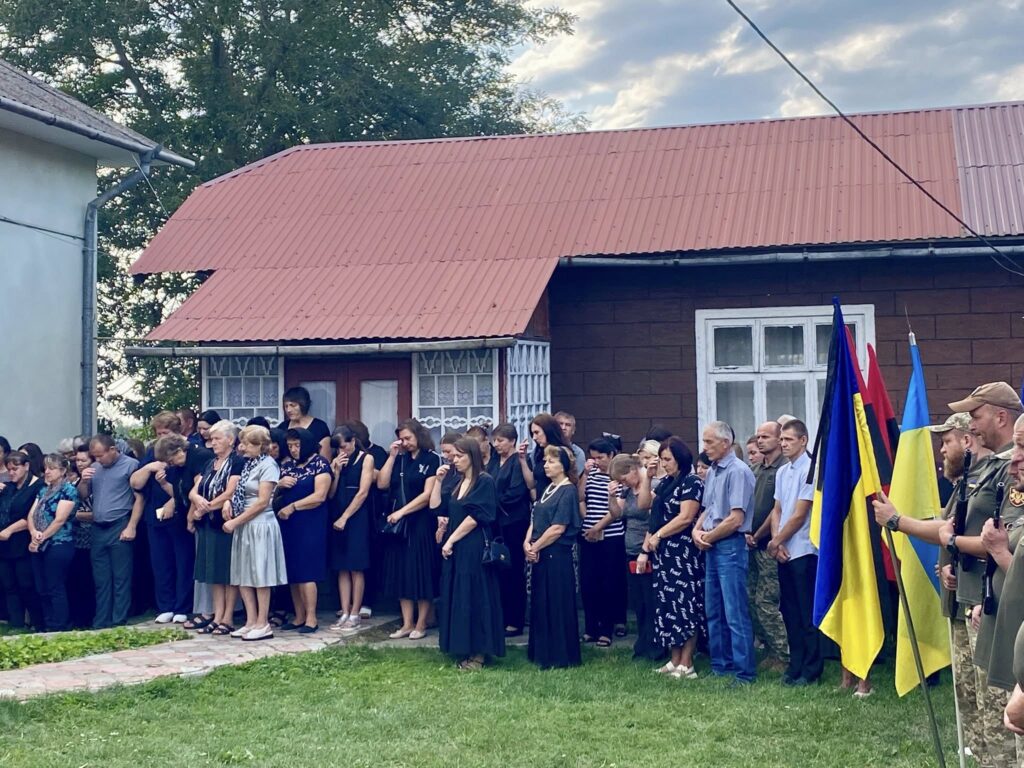 Люди стоять зі знаменами біля будинку