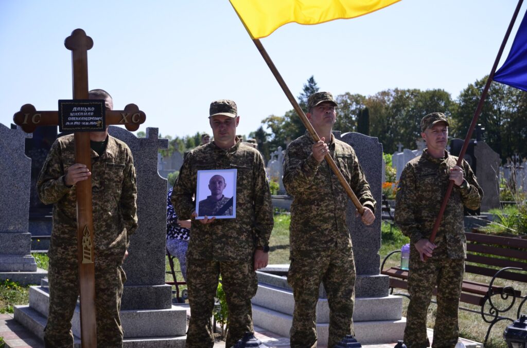 Військові на похоронах з прапорами і зображенням.