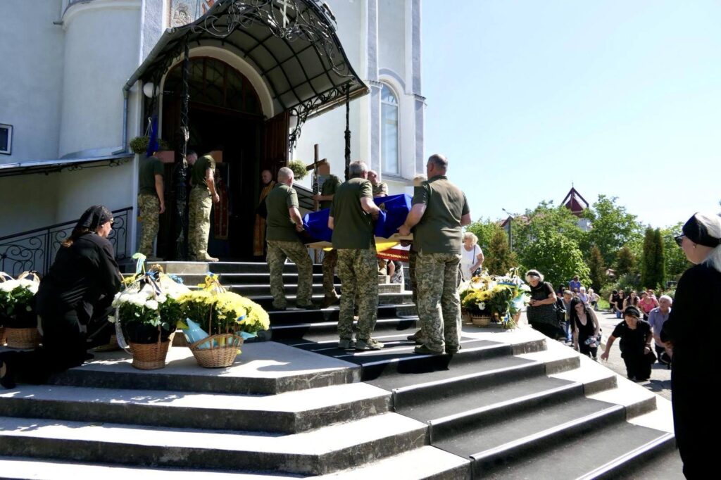 Військові несуть труну до церкви, люди вшанування