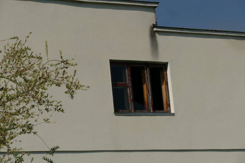 Вікно на білому фасаді будинку з гілками