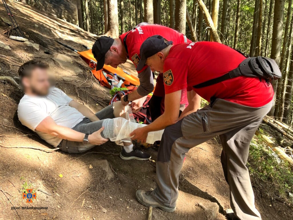 Рятувальники надають допомогу травмованій людині в лісі.