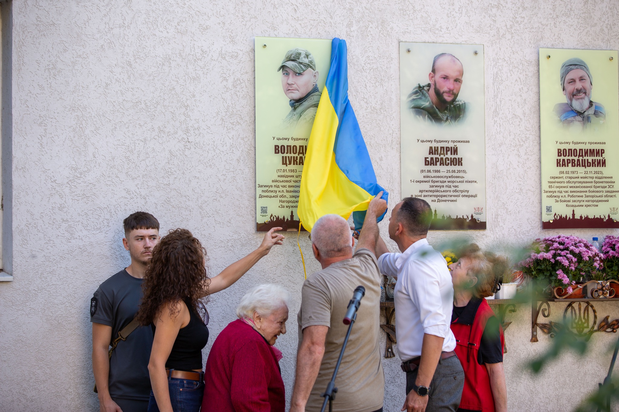 Жінка знімає прапор з меморіальної дошки.
