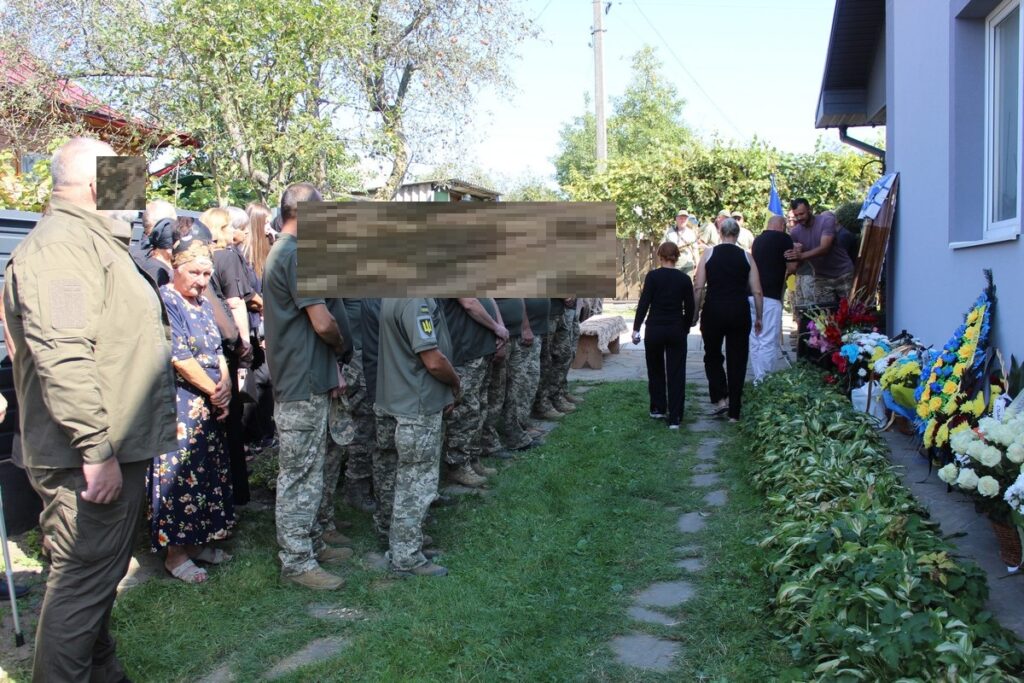 Люди на церемонії з квітами та прапорами