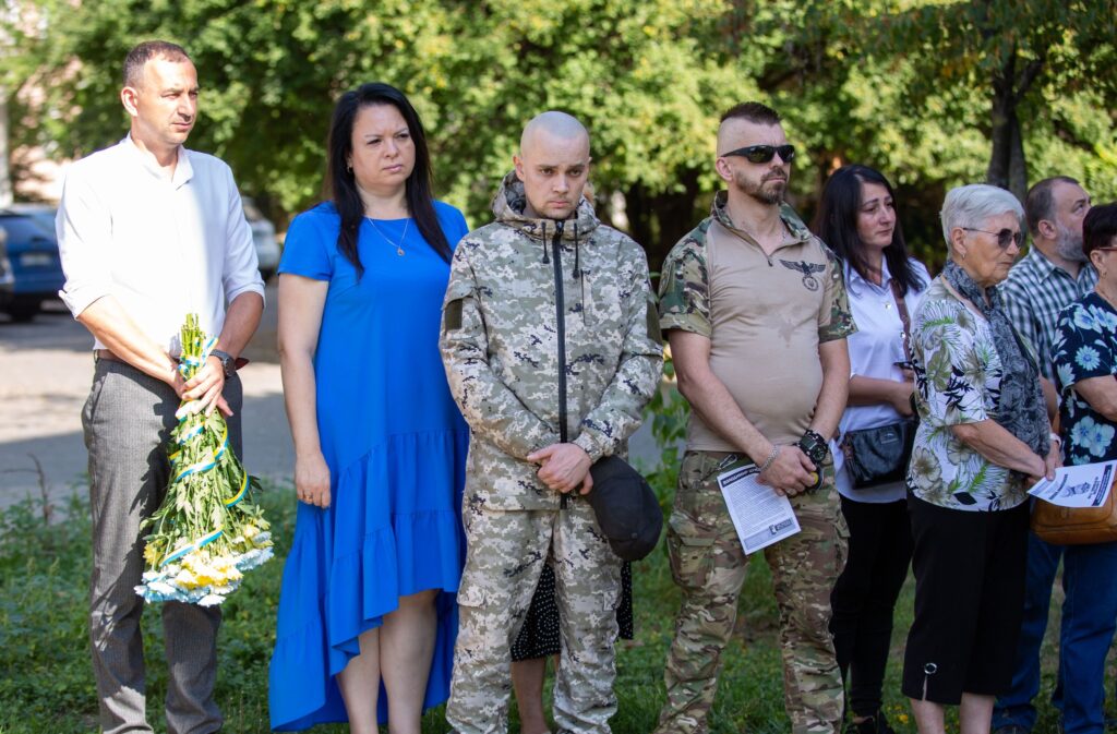 Люди на церемонії з квітами й камуфляжем