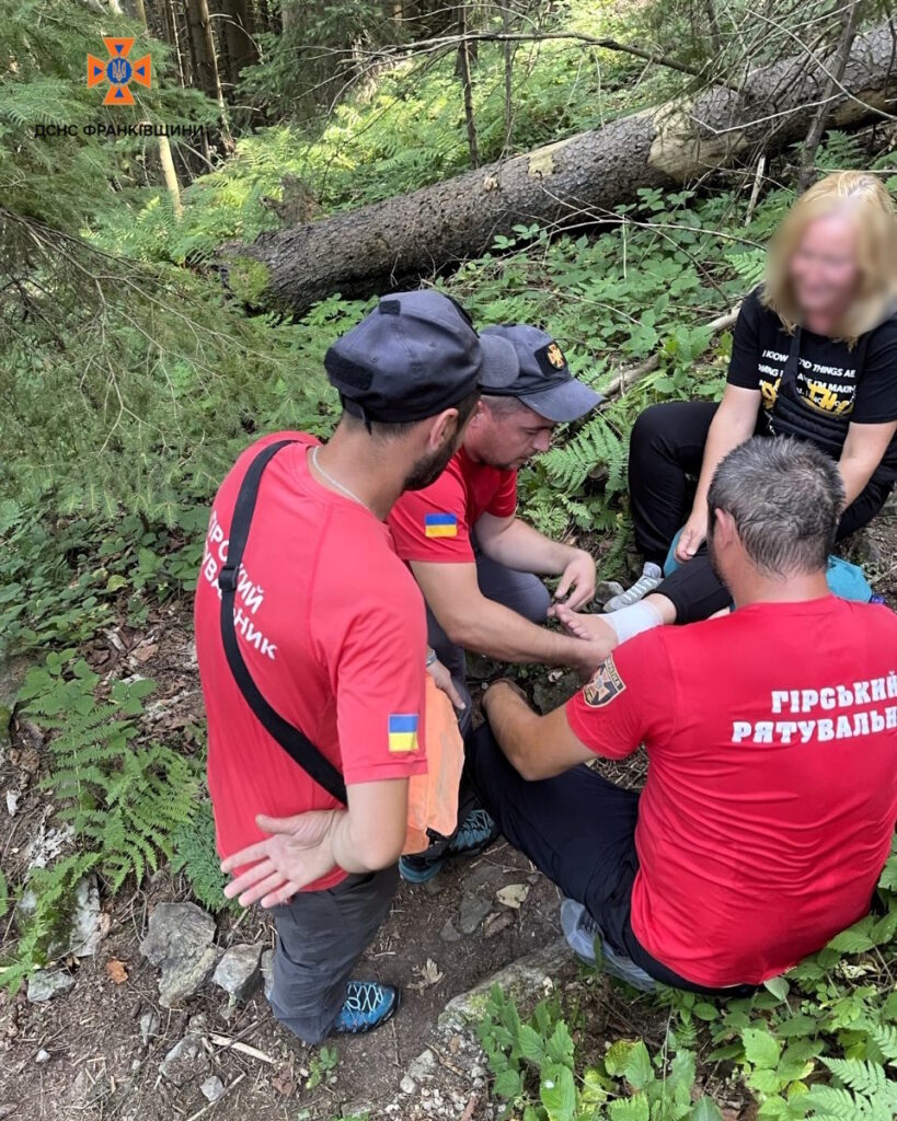 Гірські рятувальники допомагають туристу в лісі.