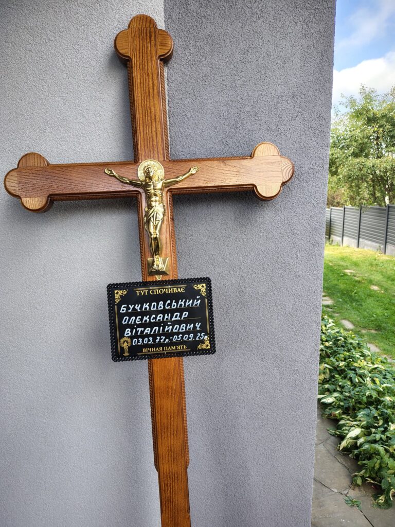 Хрест з табличкою пам'яті на стіні будинку