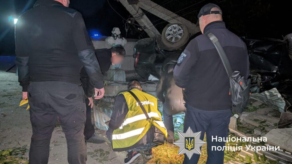 Поліцейські досліджують місце аварії автомобіля вночі.