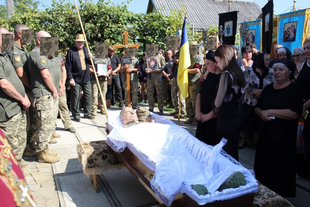 Похоронна церемонія з солдатами і людьми навколо.