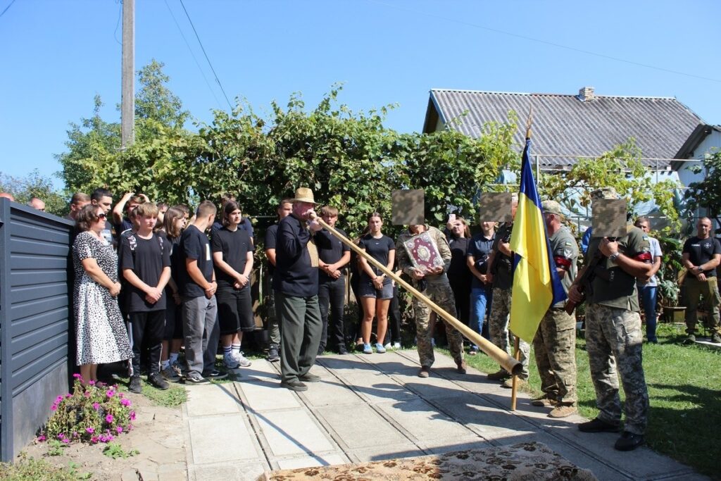 Люди біля прапора під час зборів на вулиці.