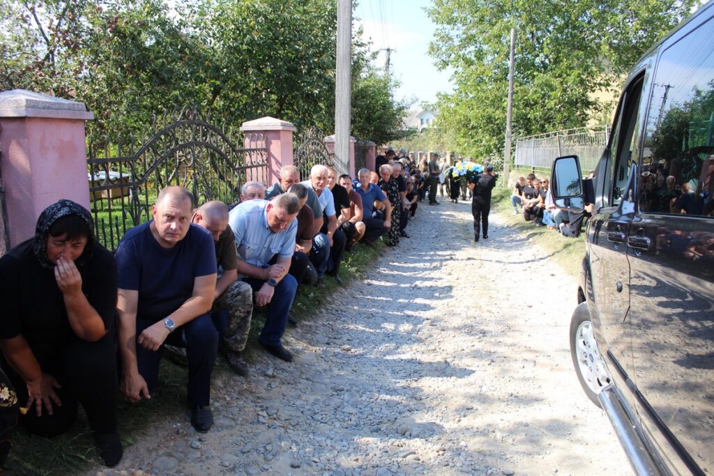 Люди вітають кортеж на сільській дорозі