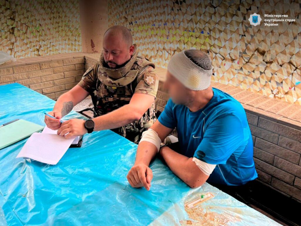 Військовий заповнює документи з пораненим чоловіком.