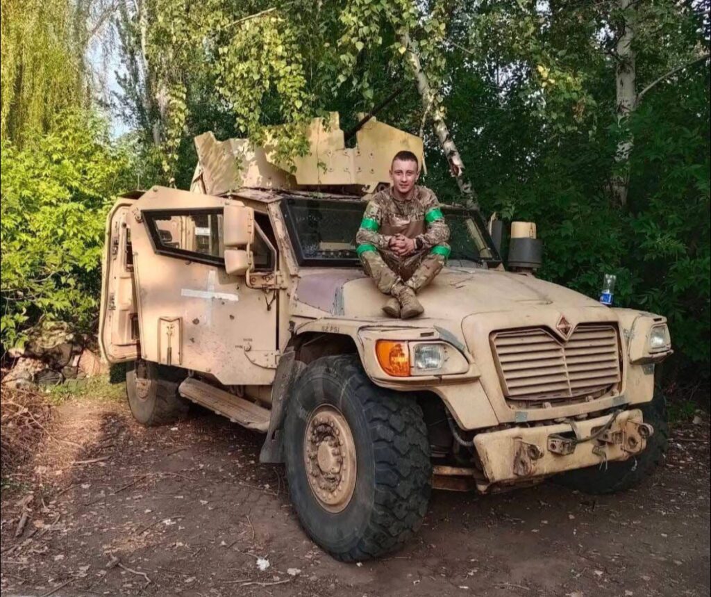 Військовий сидить на броньованій машині в лісі