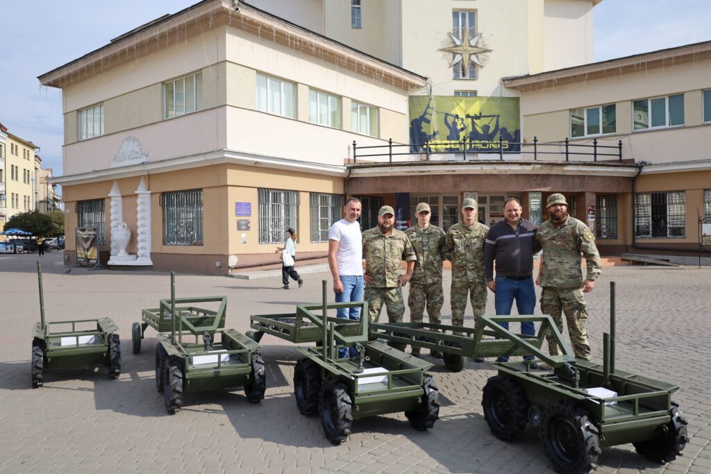Військові поруч з дронами на вулиці перед будівлею.
