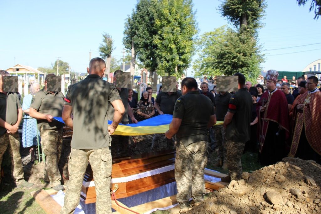 Військові на похоронах з українським прапором.