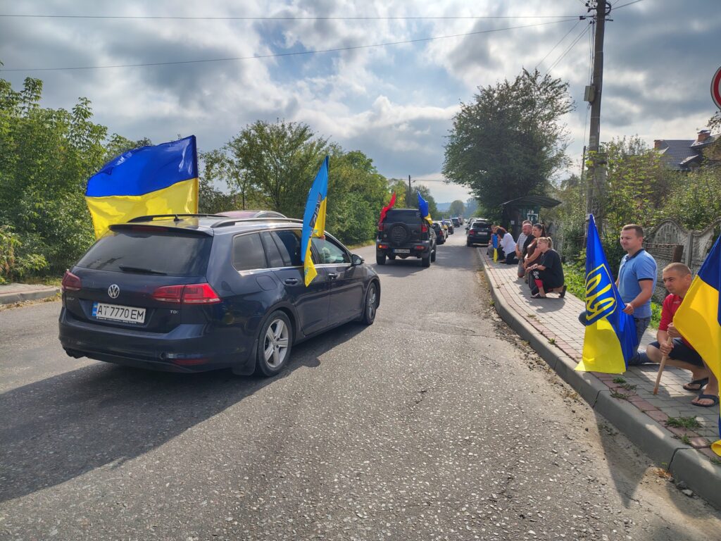 Автоколона з українськими прапорами на дорозі