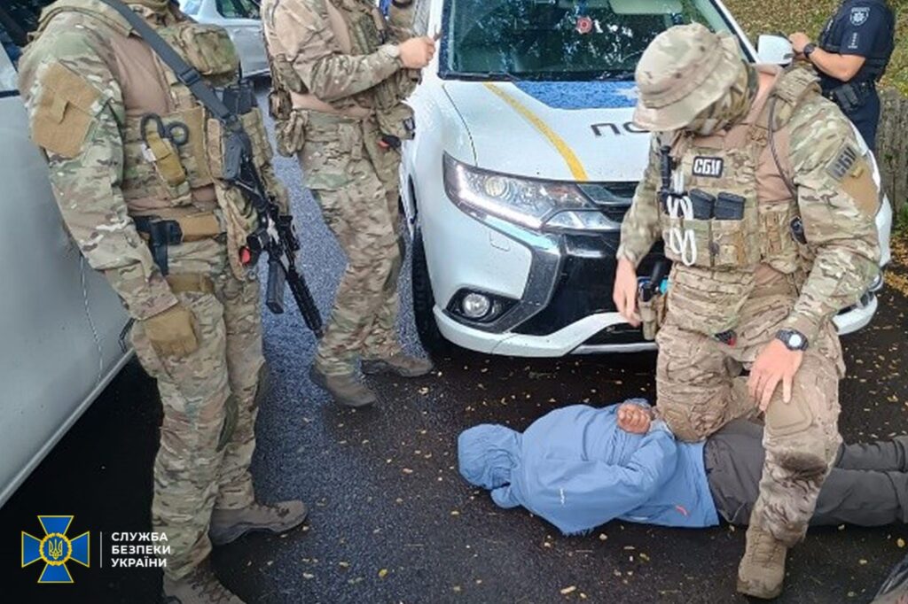 СБУ затримує підозрюваного біля поліцейського авто.