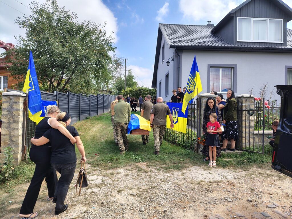Люди під українськими прапорами біля будинку