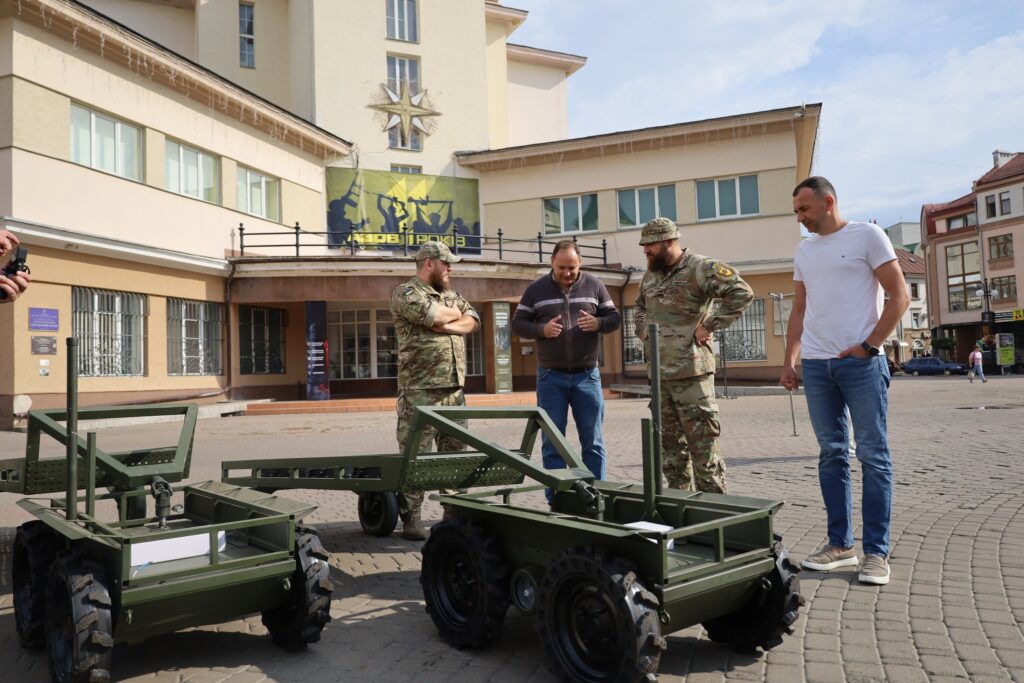 Чоловіки обговорюють військову техніку на вулиці.