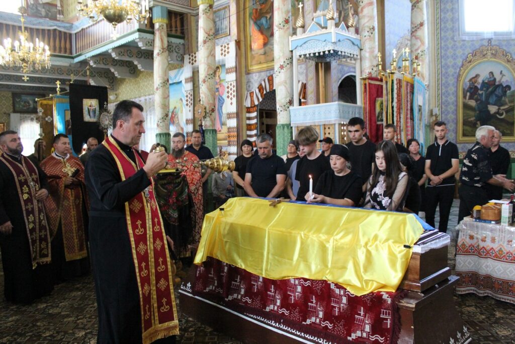 Церковна служба з труною, священик з кадилом