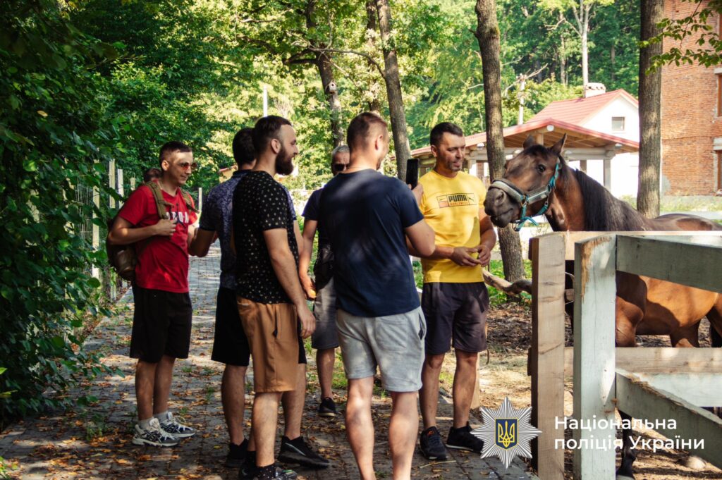 Чоловіки спілкуються біля коня у парку