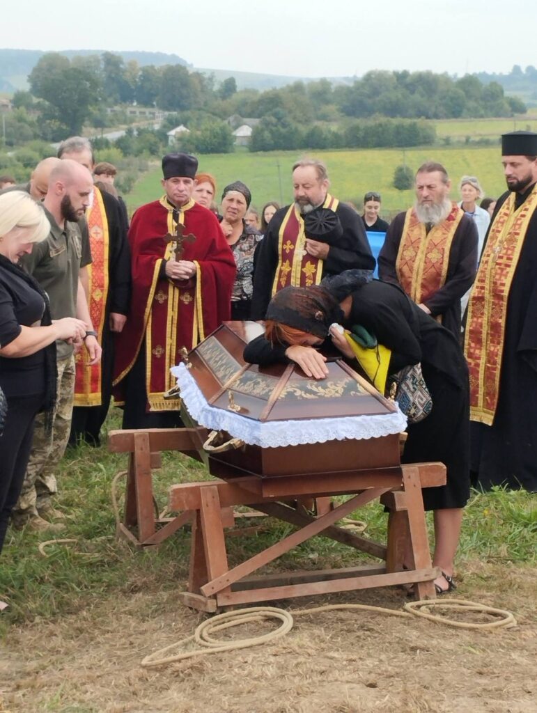 Люди на похороні з труною в полі