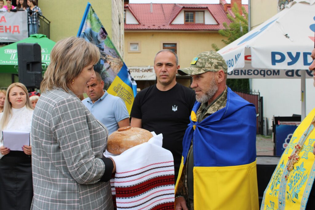 Жінка передає хліб військовому під час церемонії.
