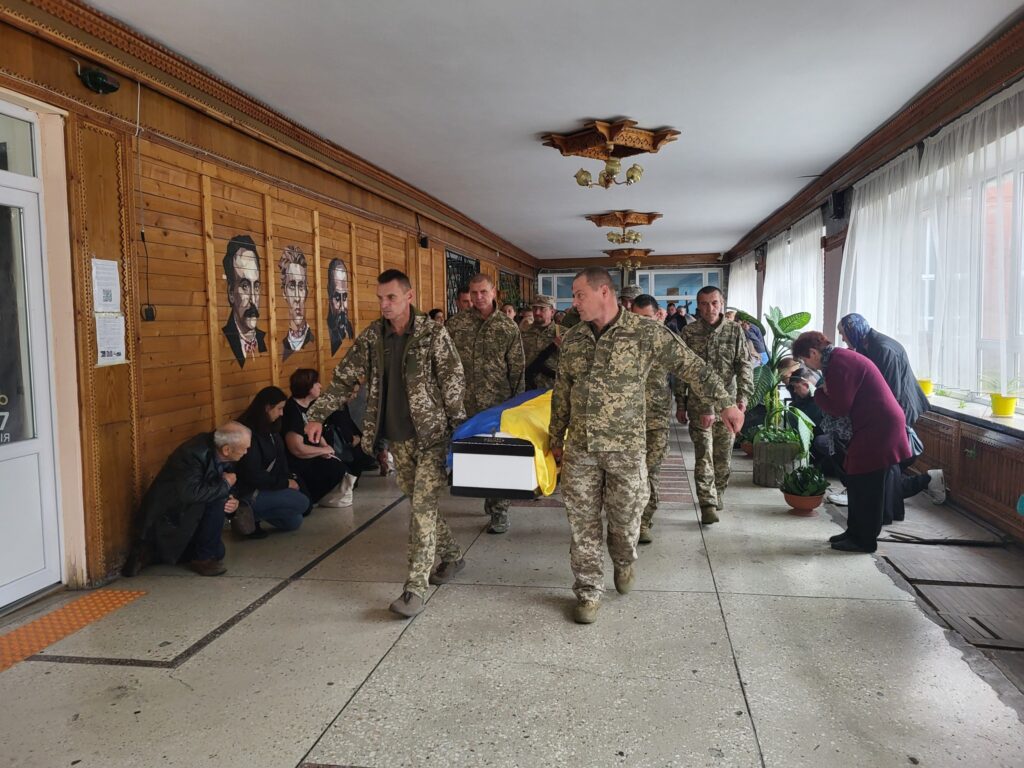 Військові несуть труну з прапором України.