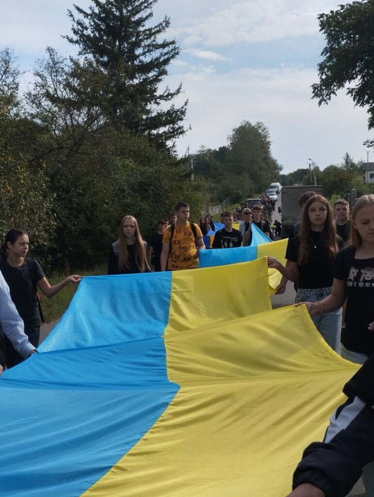 Люди несуть великий прапор України на вулиці.