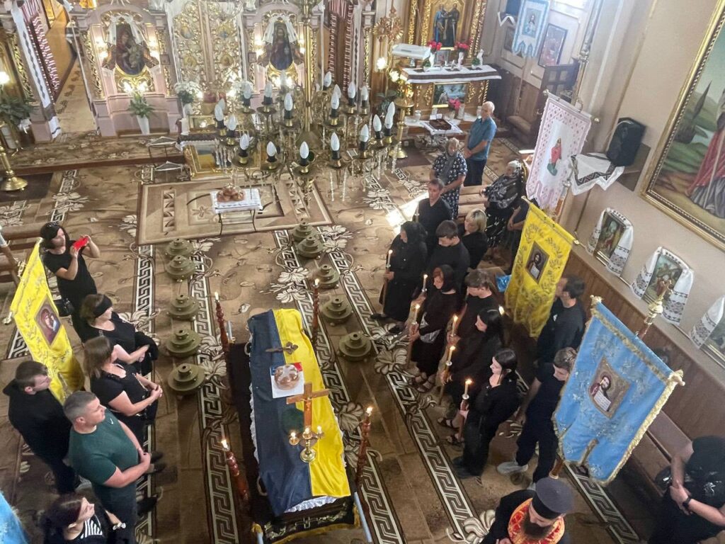 Вшанування у церкві, люди зі свічками біля труни