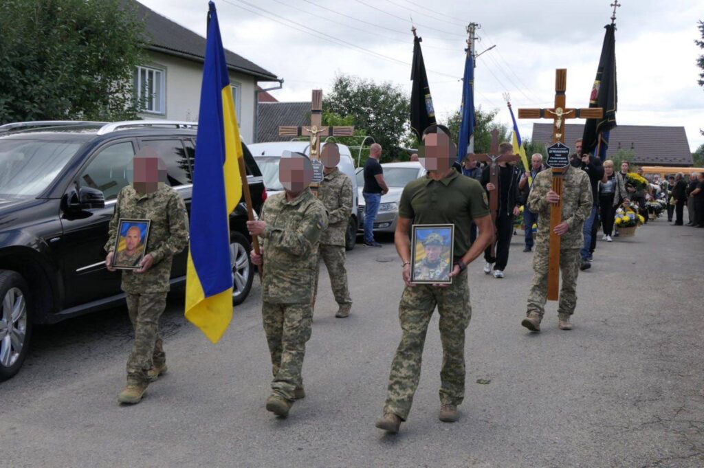 Військовий похорон з прапорами та портретами героїв.