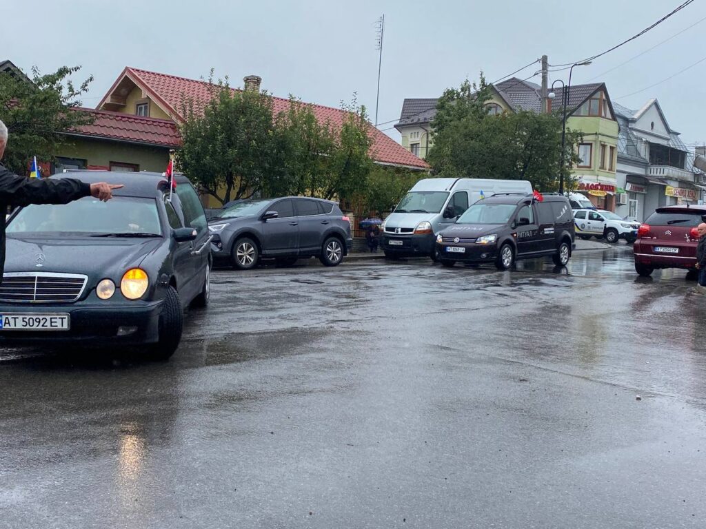 Автомобілі на дощовій вулиці біля будинків.
