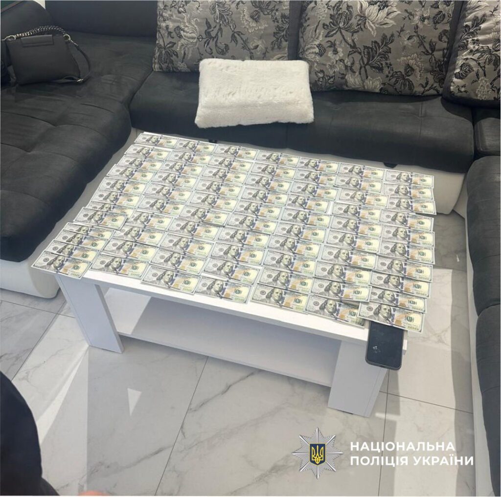 Гроші на столі і чорна сумка на дивані.