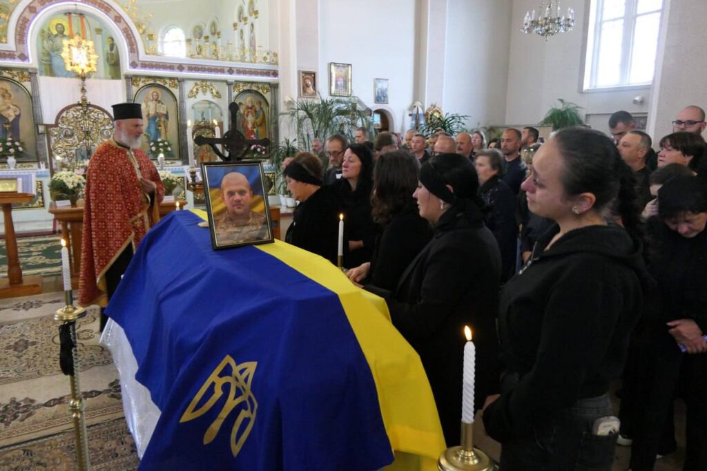 Церемонія прощання в церкві з українським прапором.