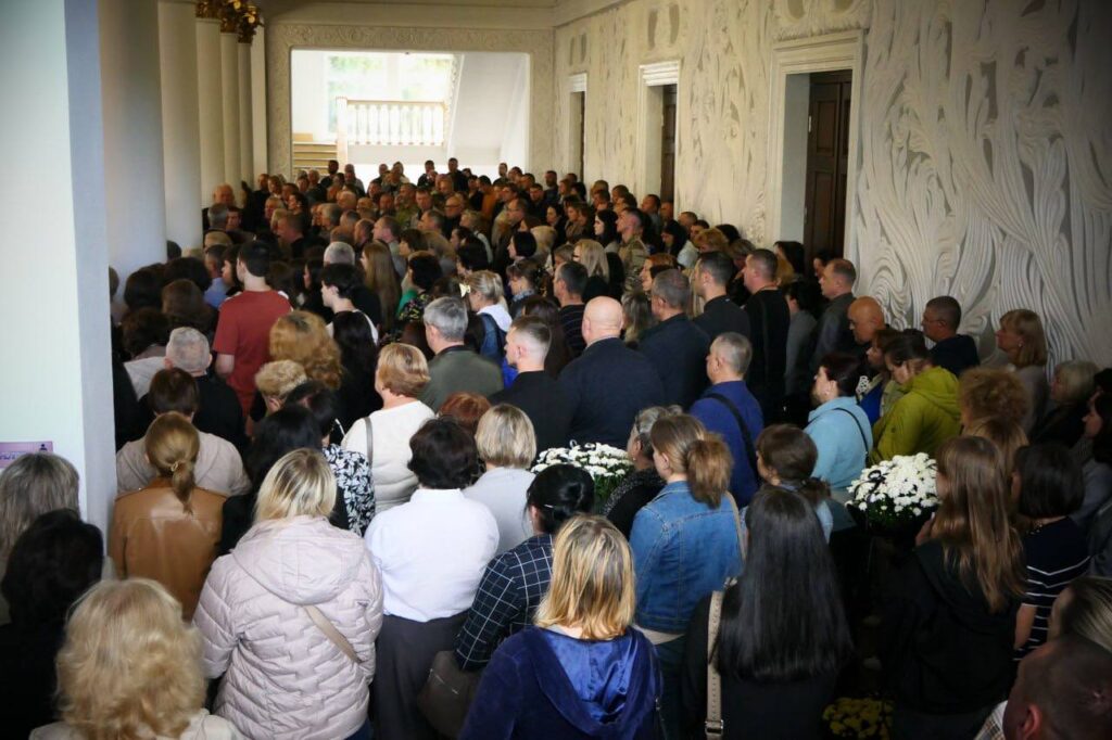 Група людей зібралася у коридорі будівлі.