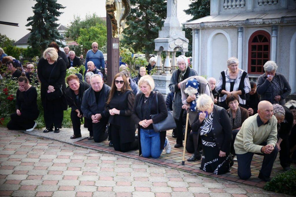 Люди на колінах перед церквою в жалобі
