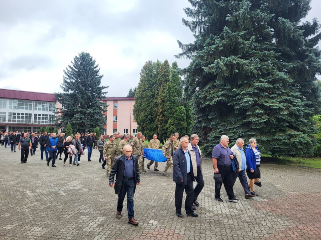 Люди йдуть поруч з великими деревами на вулиці.