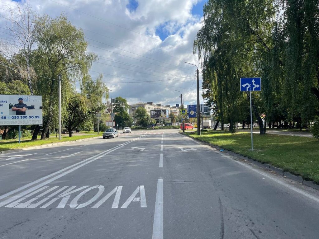 Дорога зі знаком повороту і зеленими деревами