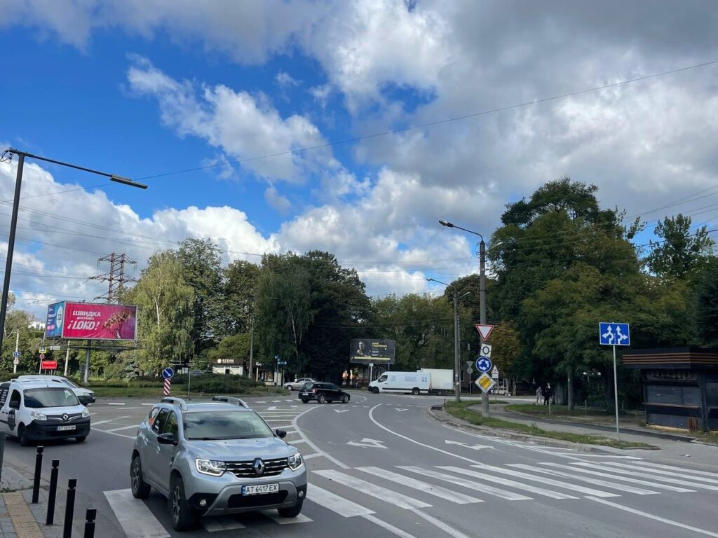 Вулиця з автомобілями та перехрестям під хмарним небом.