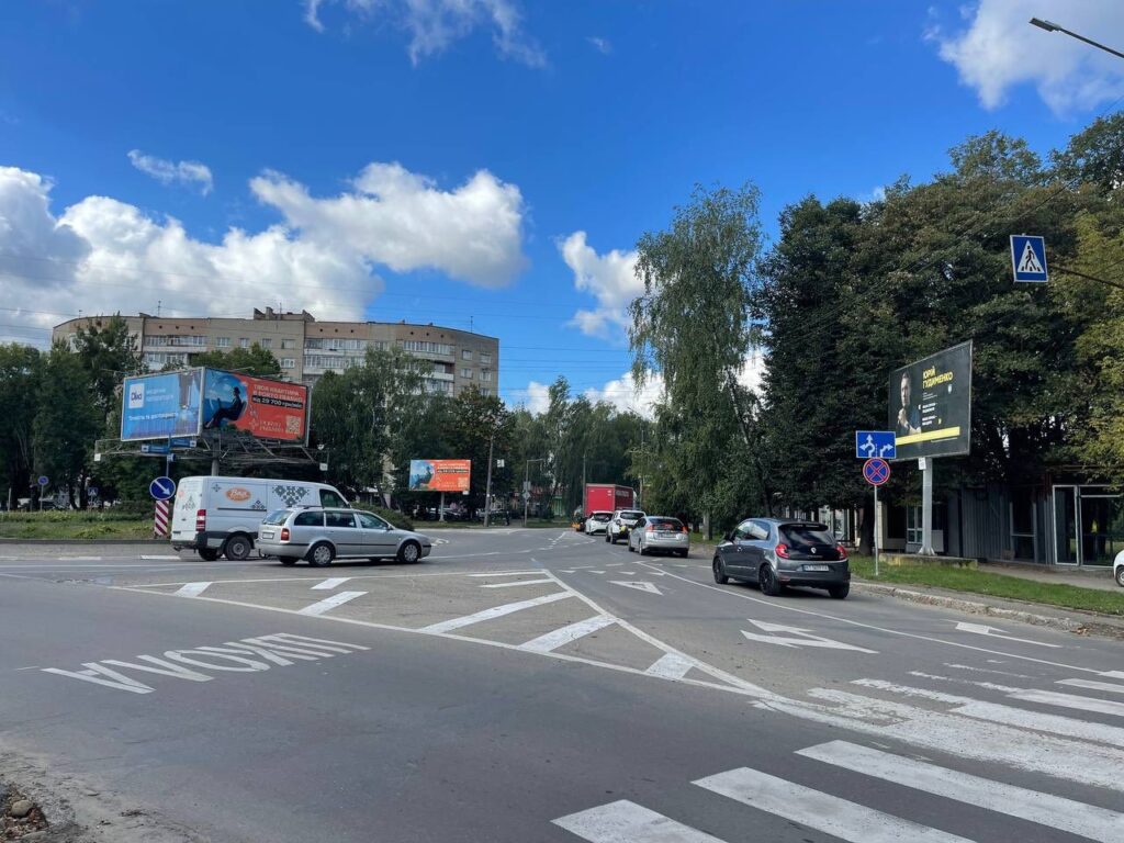 Перехрестя дороги з автомобілями та рекламою будинків.