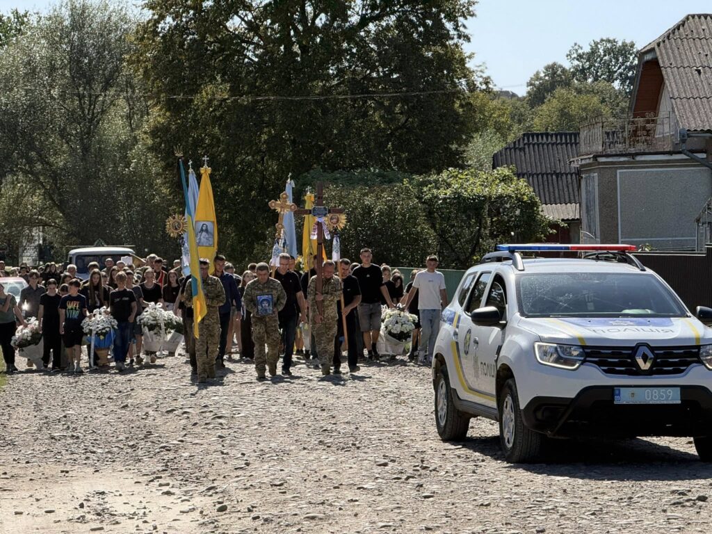 Похоронна процесія з прапорами України та поліцією.