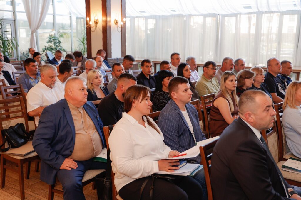 Люди на конференції в залі з вікнами.