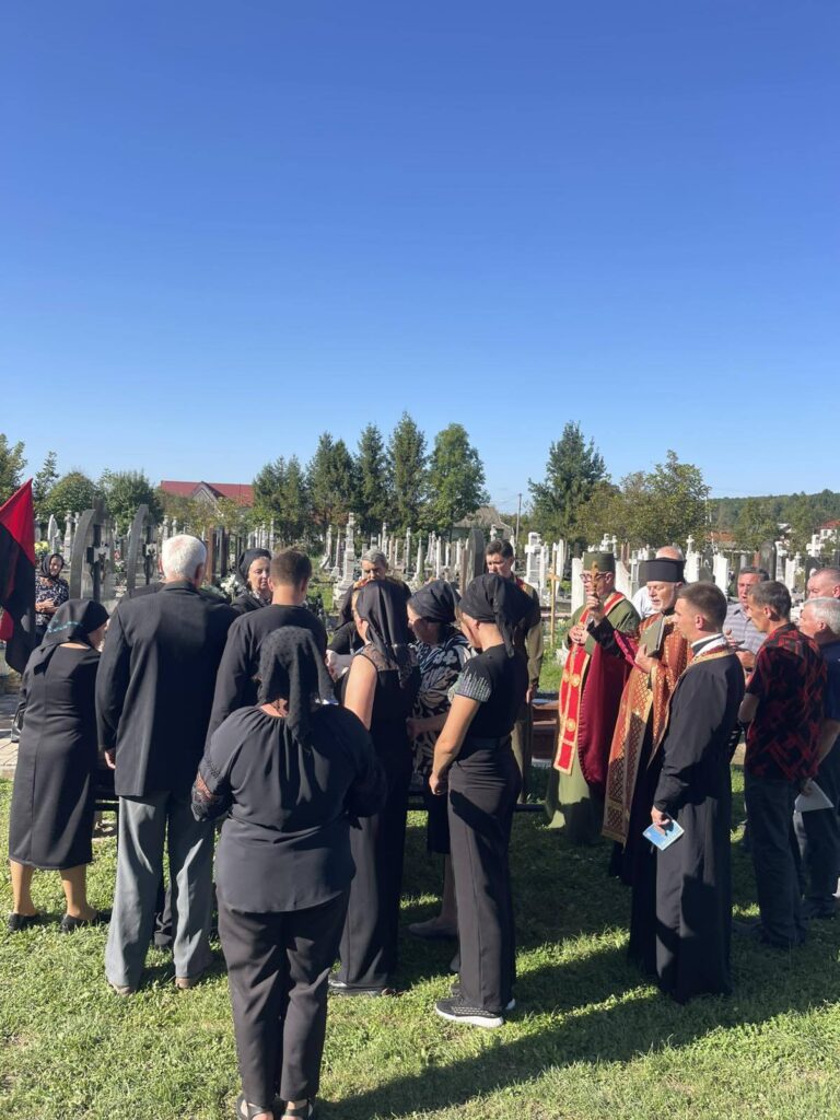 Люди зібрались на кладовищі під час похорону.
