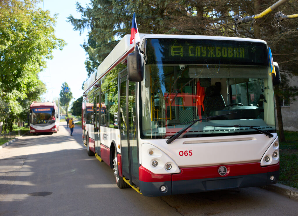 Тролейбус на вулиці міста з деревами.