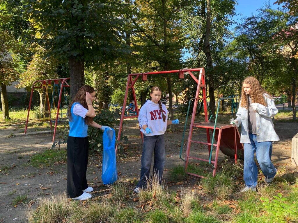 Дівчата прибирають дитячий майданчик у парку.