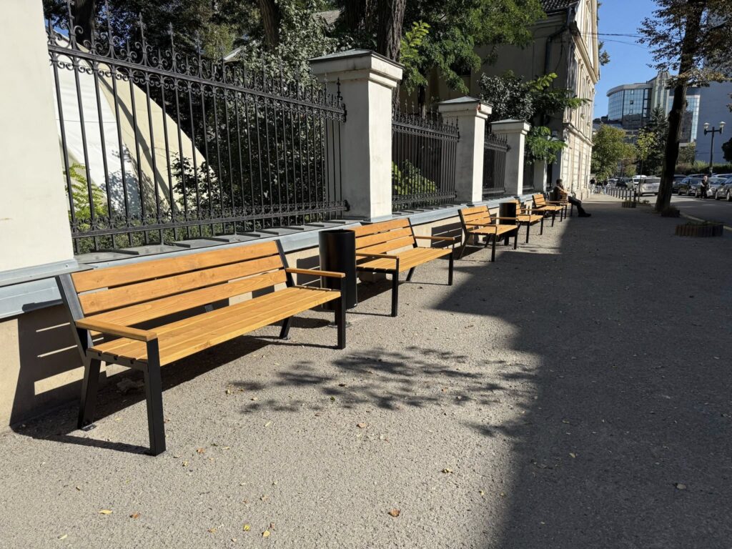 Дерев'яні лавки вздовж тротуару біля паркану